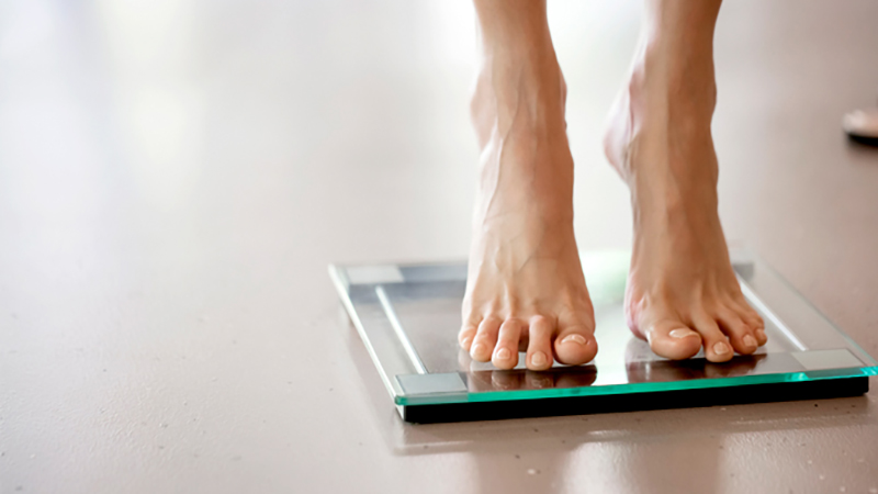 person on toes standing on glass scales