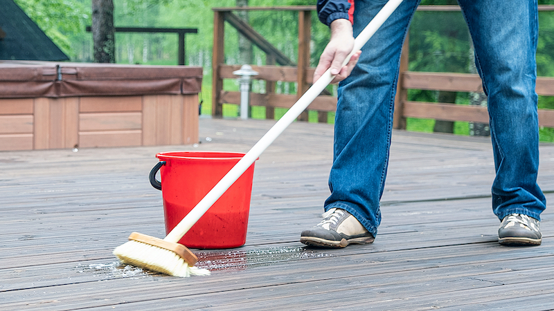 man cleaning a patio with a broom