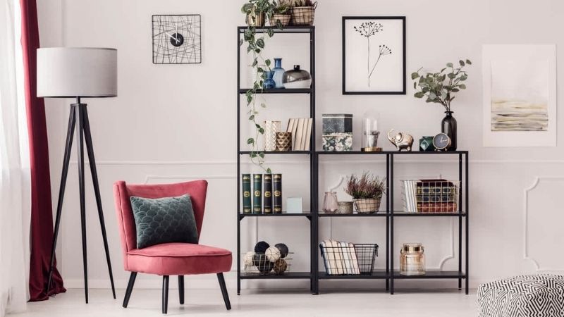 Black bookshelf with a pink chair and flowerpots